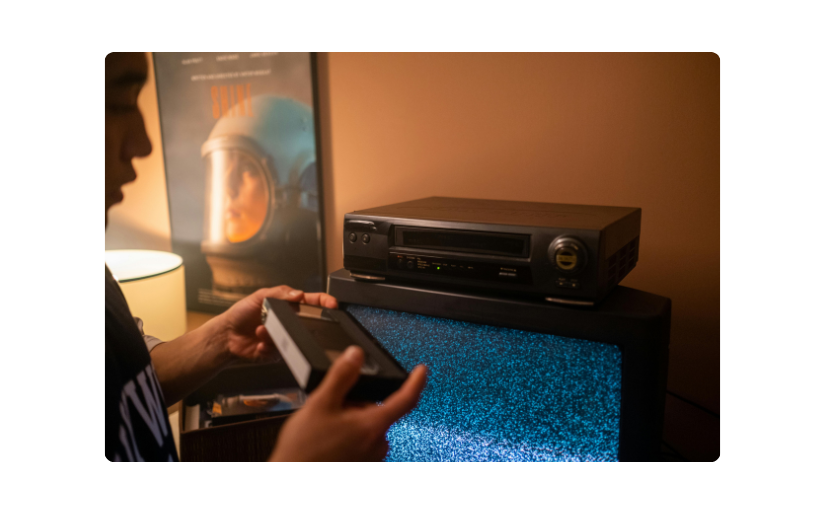 Hombre configurando un VCR para ver un casete, destacando la electrónica vintage popular en la reventa de eBay.